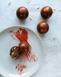 Marses chocolate spheres scattered around and one sectioned on a plate