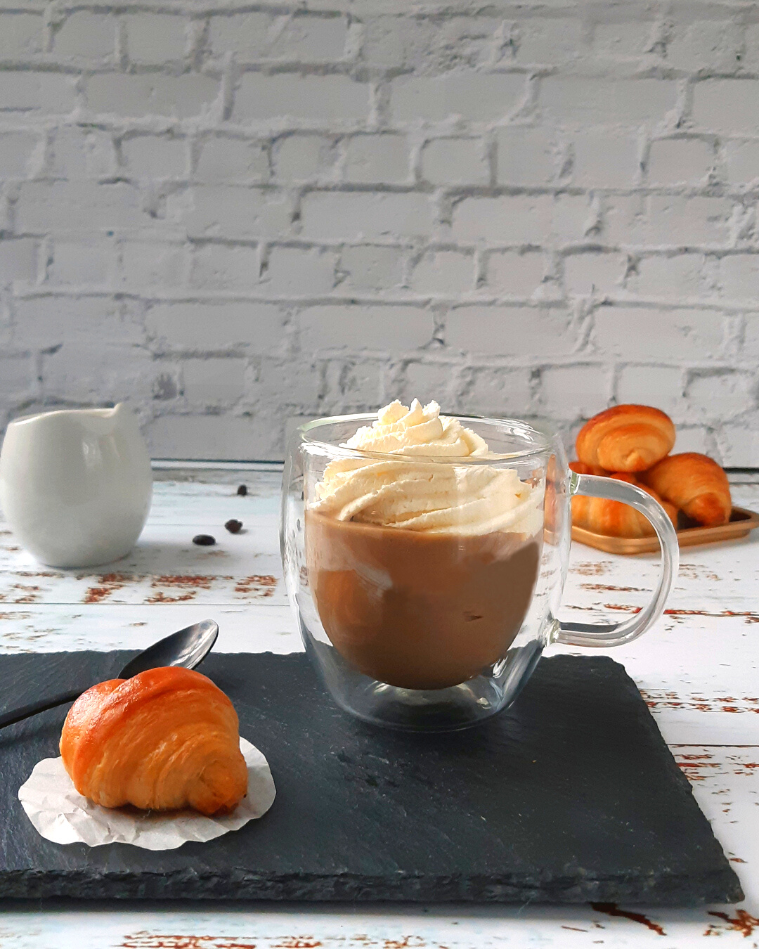 Mini croissant on a slate with a cup of "cappuccino", coffee pastry cream and whipped cream