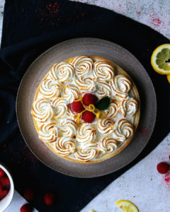 Raspberry and Lemon white chcolate mousse tart seen from the top with swirly torched italian meringue