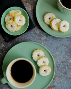 Canestrelli biscuits laid on two turqoise plates, with cups of coffee nextto them