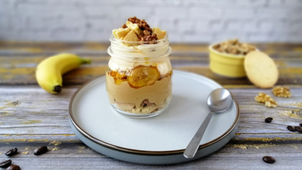 A jar of coffe and mascarpone cream mess with caramelized bananas and walnuts on plate