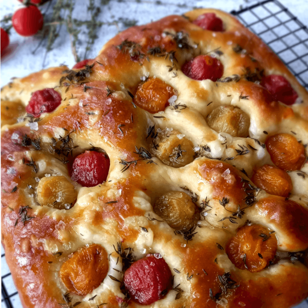 Close up photo of a pickled rainbow cherry tomato and thyme focaccia