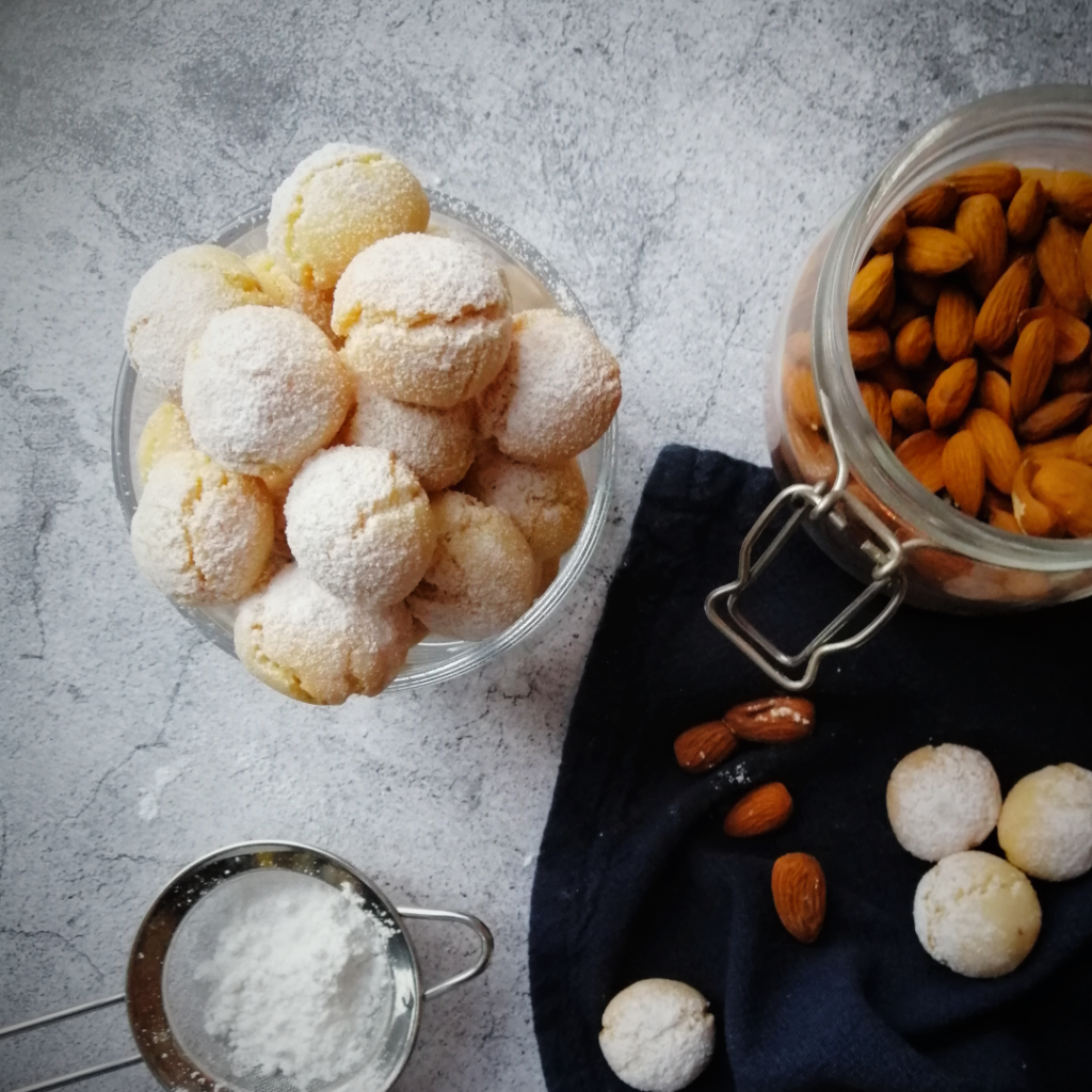 Amaretti biscuits in a jar with some icing sugar and almons in the background. Copyright: the Italian baker