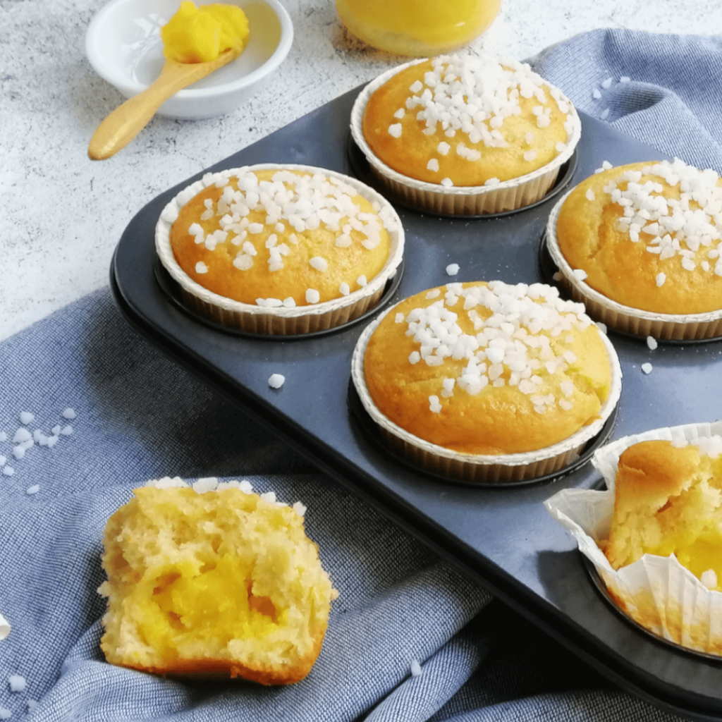 Lemon curd muffin half with whole muffins and lemon curd spoon